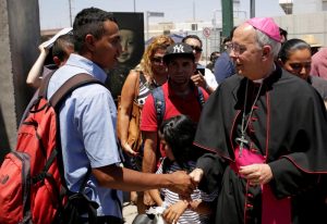 Bishop Mark J. Seitz of El Paso, Texas, greets a Salvadoran migrant June 27, 2019. Bishop Seitz walked and prayed with a group of migrants at the Lerdo International Bridge in El Paso as they sought asylum in the U.S. (CNS photo/Jose Luis Gonzalez, Reuters) See BORDER-BISHOP-BRIDGE June 27, 2019.